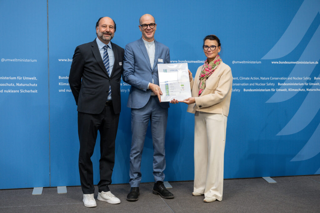 Ehrung der Stadt Berlin auf dem 3. Platz der „Recyclingpapierfreundlichsten Städte“ 2026, v.l.n.r.: Marc Gebauer (Sprecher der Initiative Pro Recyclingpapier), Benjamin Bongardt (Referatsleiter MVKU der Stadt Berlin), Parlamentarische Staatssekretärin Rita Schwarzelühr-Sutter ©IPR/Mark Bollhorst