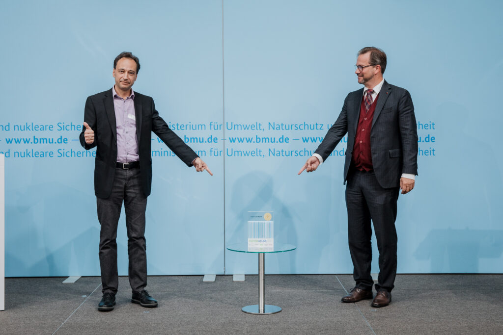 Thilo Schnor, Erster Bürgermeister der Stadt Solingen, nimmt den Award für die Auszeichnung als "Recyclingpapierfreundlichste Stadt" von Parlamentarischer Staatssekretär Pronold entgegen. © BMU/Sascha Hilgers